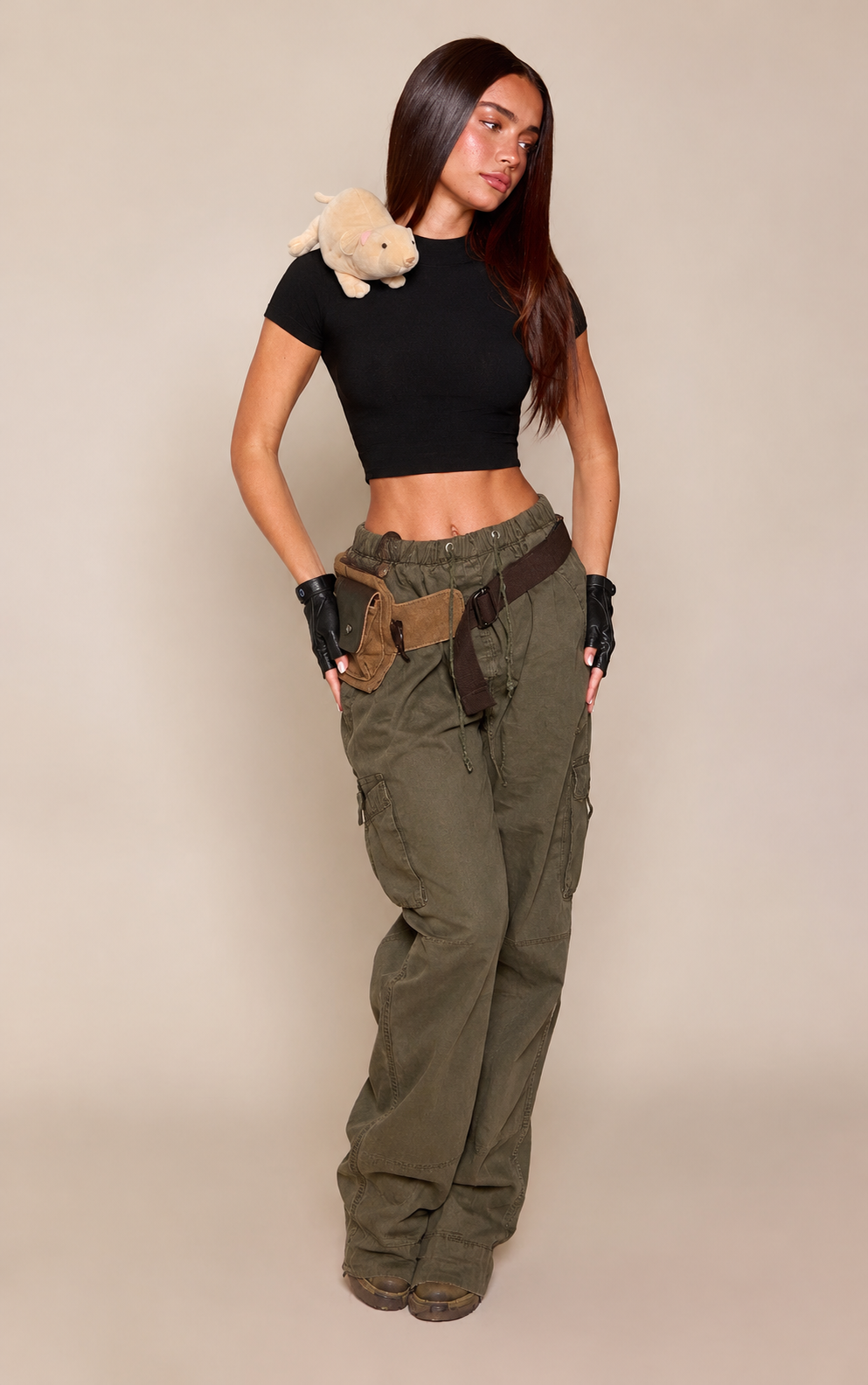 Look inspirado en Kim Possible con top negro corto, pantalón cargo verde oliva, guantes negros y cinturón con bolsillos.